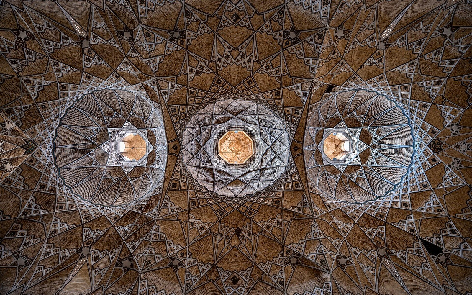 The vaulted brick run of a covered bazaar, light dropping through roof openings