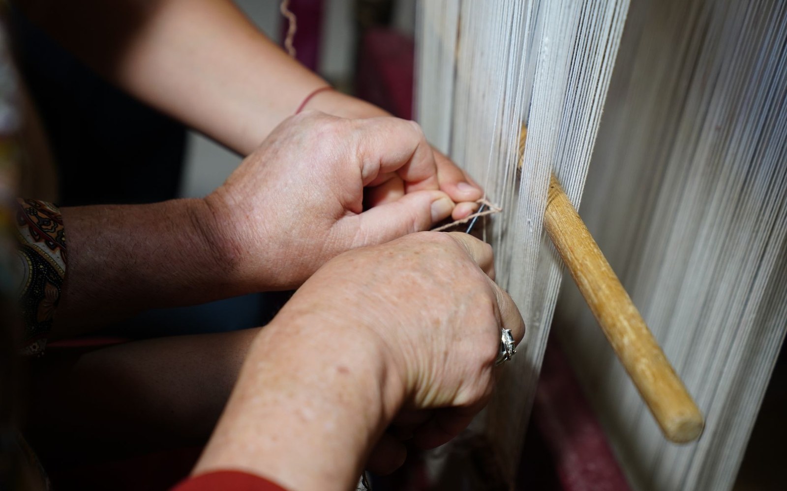 A weaver's hands at the knots, the pattern standing above them