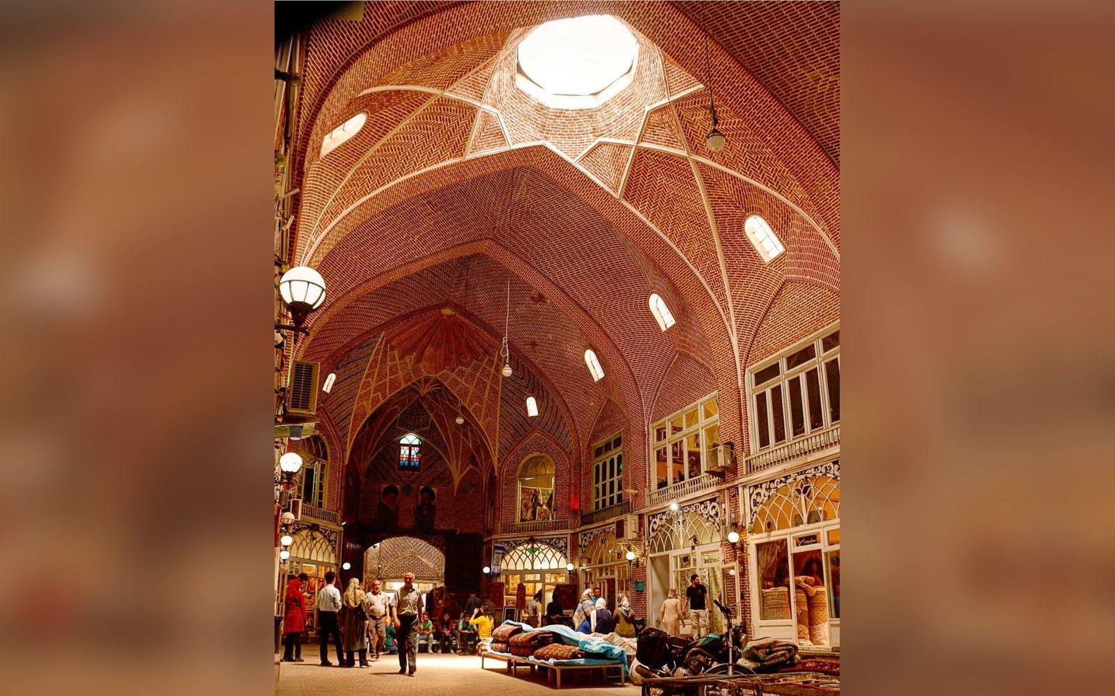 Domed brick vaulted ceiling with skylight over a bustling covered bazaar corridor
