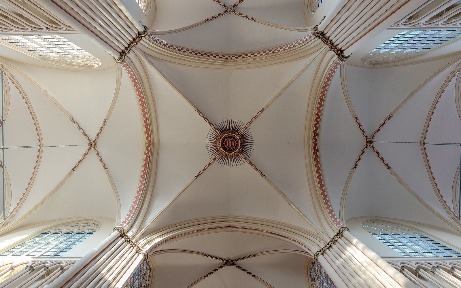 Ribbed vaults meet at a sunburst medallion in a cathedral ceiling